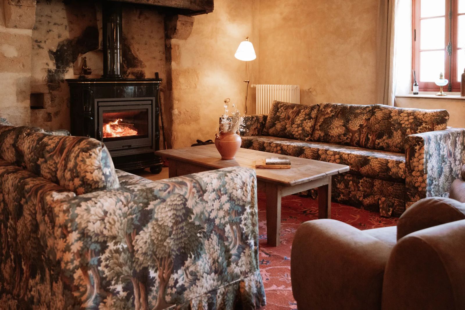 Grand salon avec poêle en céramique allumé et canapés — Maison Oiserie