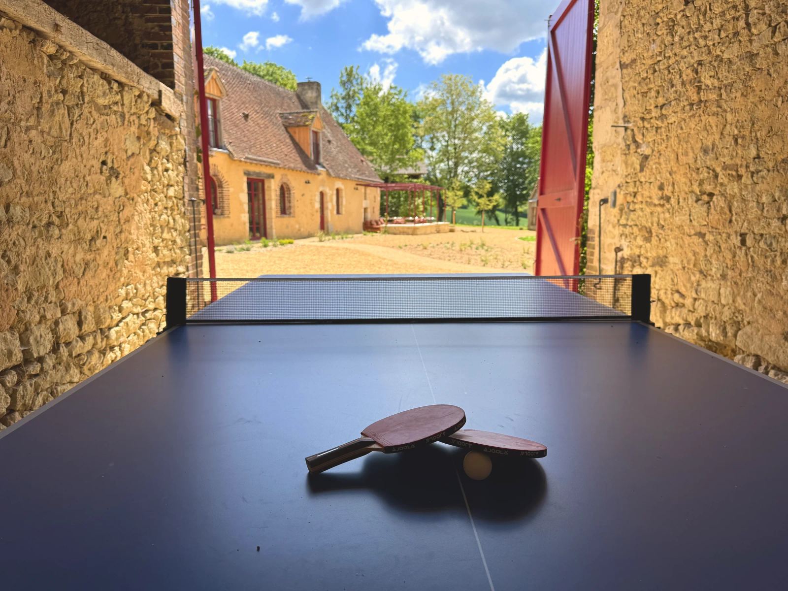 Table de ping-pong dans la cour, bâtiments en pierre — Maison Oiserie