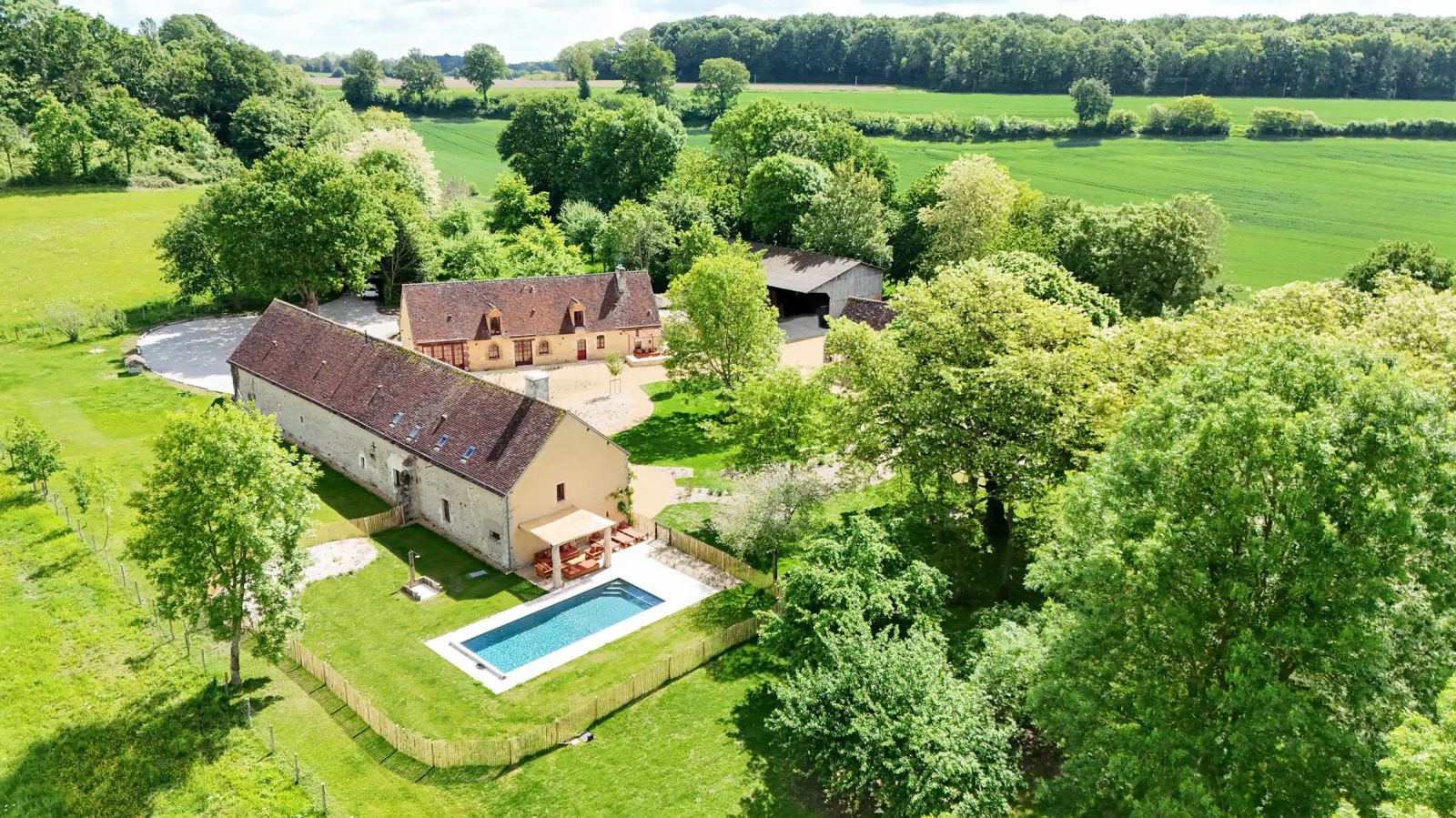 Vue aérienne de Maison Oiserie : corps de ferme restauré, piscine et prairies du Perche